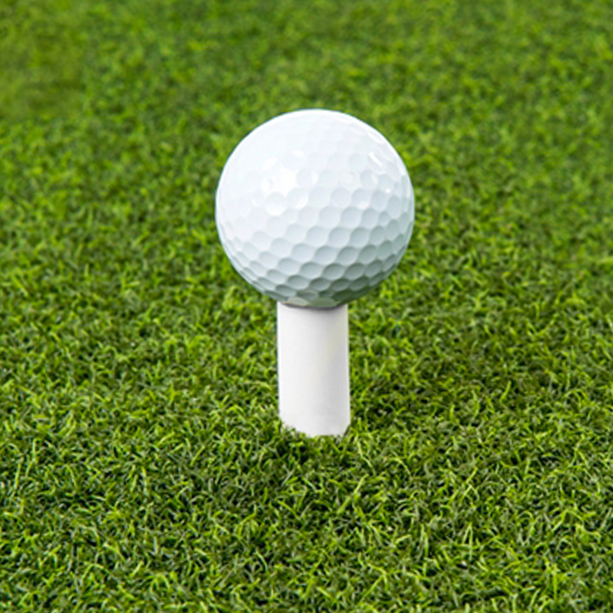 A golf ball placed on a tee on a grassy field.