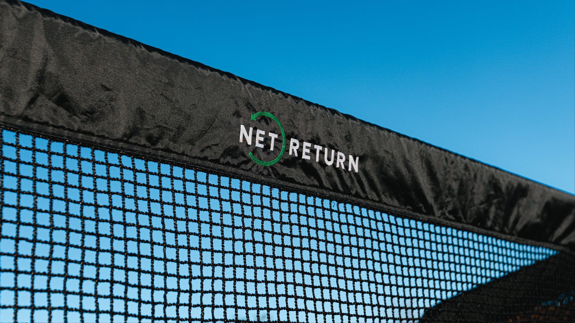 Close-up of golf net with 'Net Return' branding against a blue sky.
