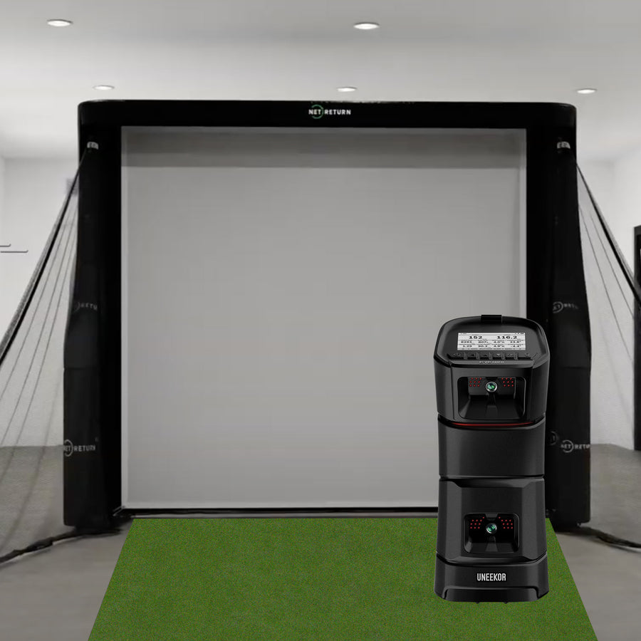 Indoor golf simulator setup with a large screen, netting, and a launch monitor on a green mat.