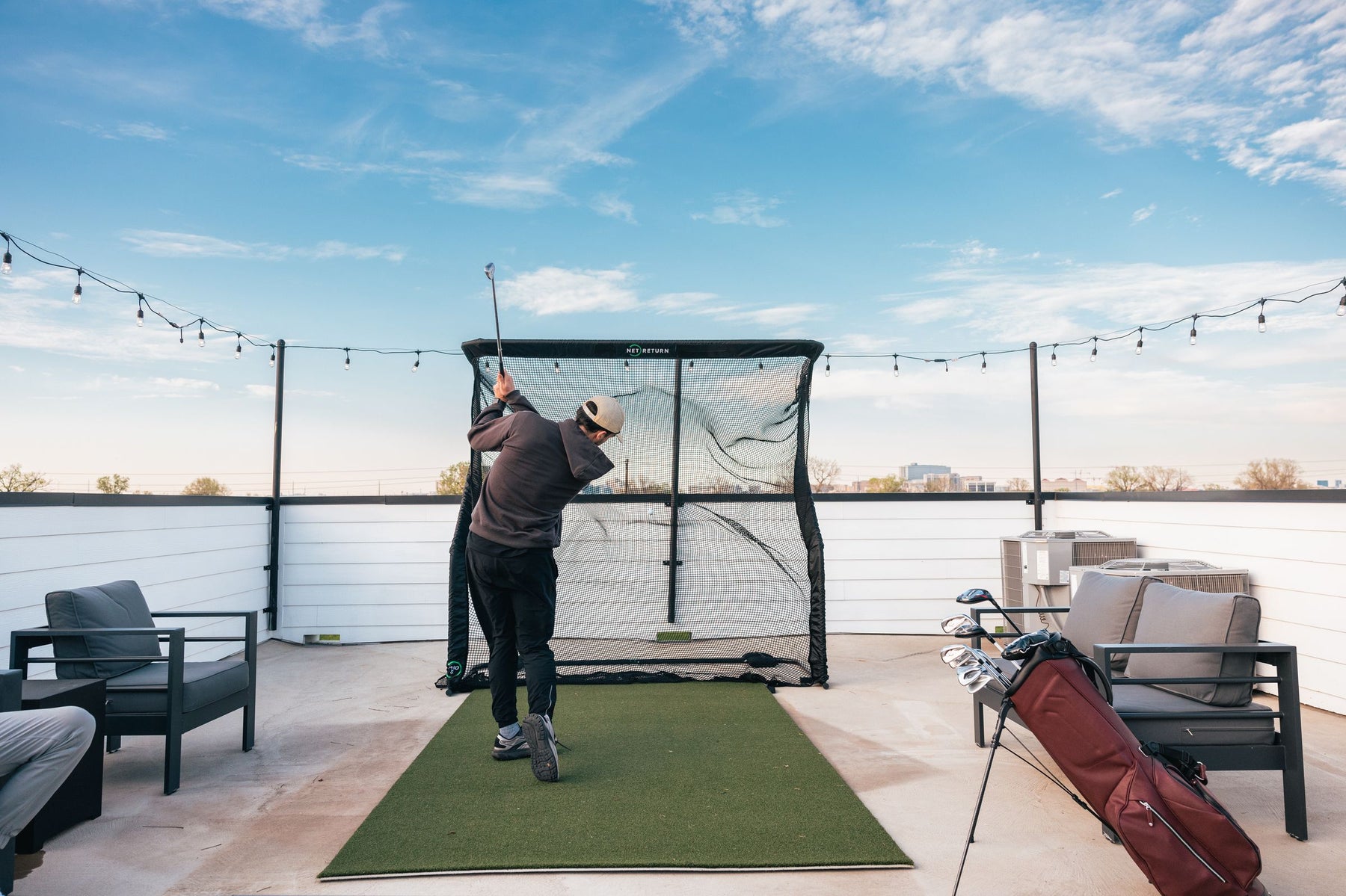 Dad hitting golf balls into a Net Return net in his backyard