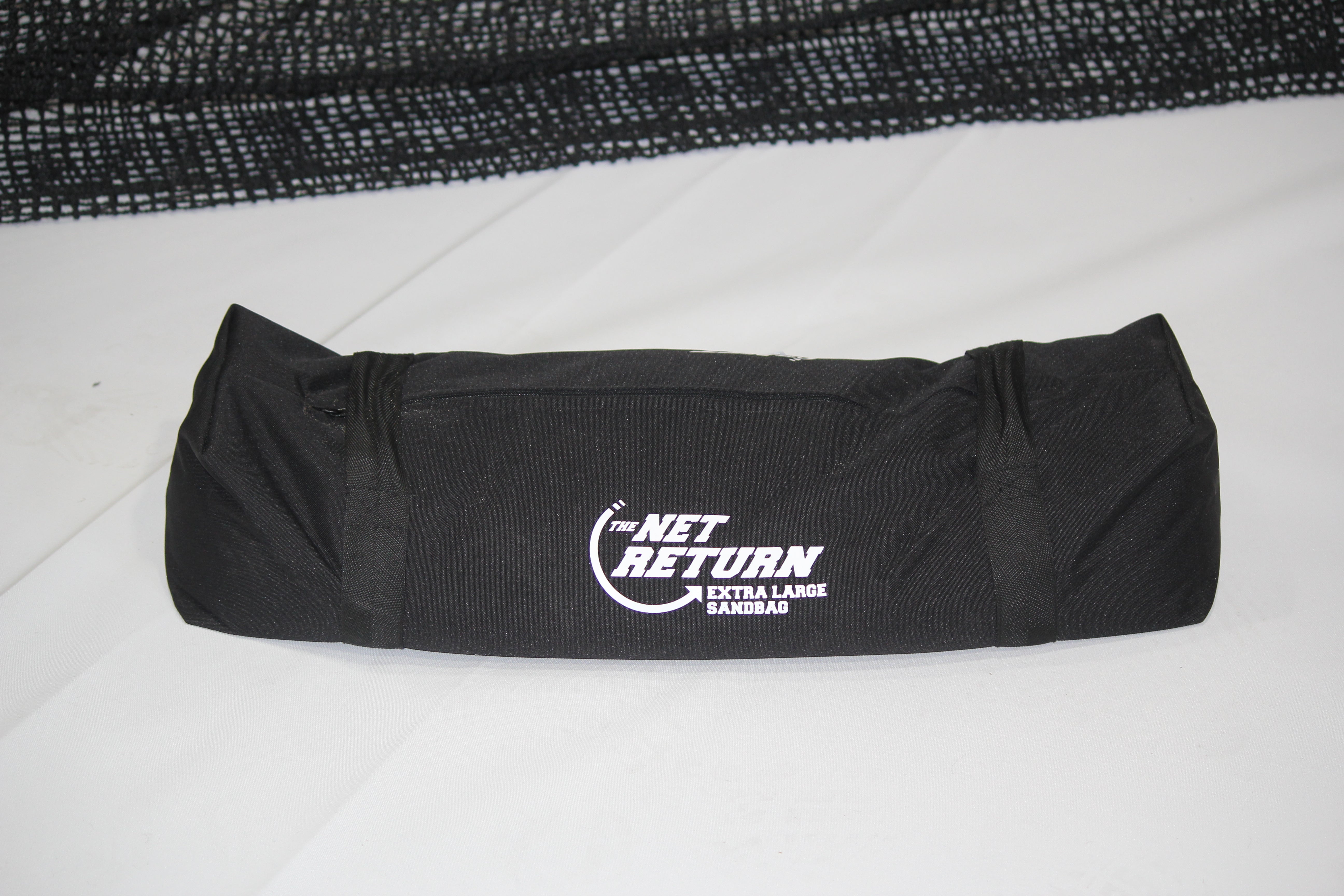 A black sandbag with "The Net Return Extra Large Sandbag" printed on it, lying on a white surface.