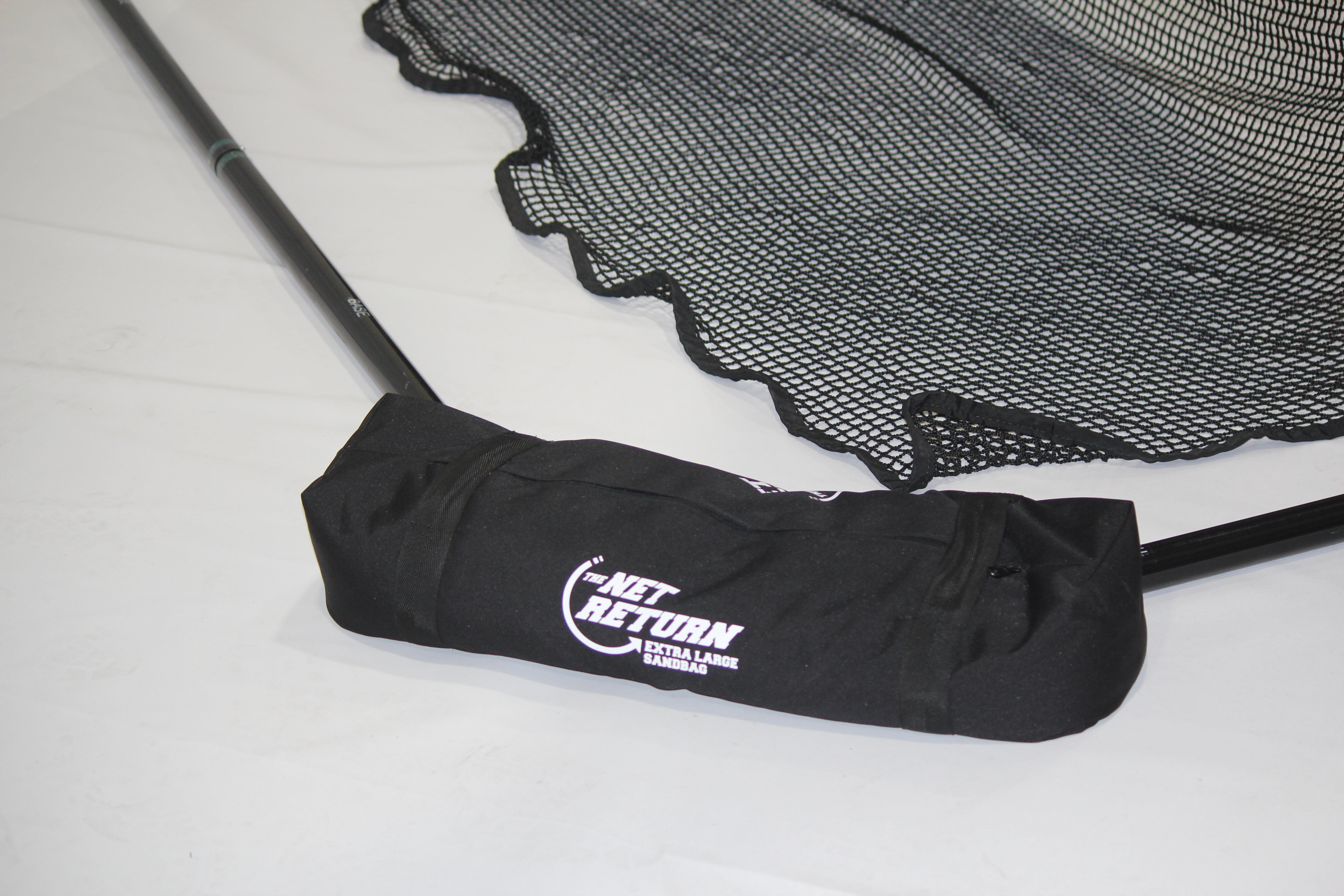 A black net with a metal frame and a black carrying bag labeled "The Net Return Pro Series" on a white surface.
