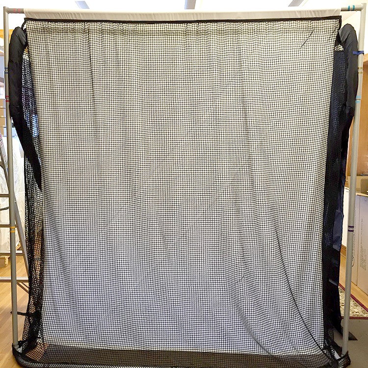 A large black and white checkered curtain is draped across a metal frame, with black fabric draped on either side.